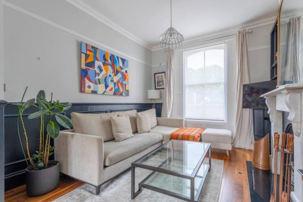 a living room with a couch and a glass table at Stylish 2 Bedroom Home in Islington with Garden in London