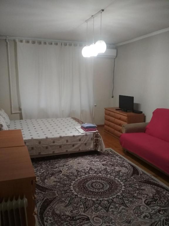 um quarto com duas camas e um sofá vermelho em 1-к. Карасай батыра 110 em Almaty