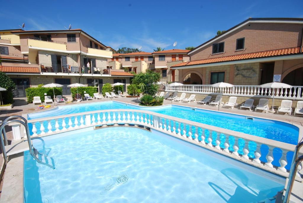 uma grande piscina com cadeiras e um edifício em Residence Il Borgo em Tortoreto Lido