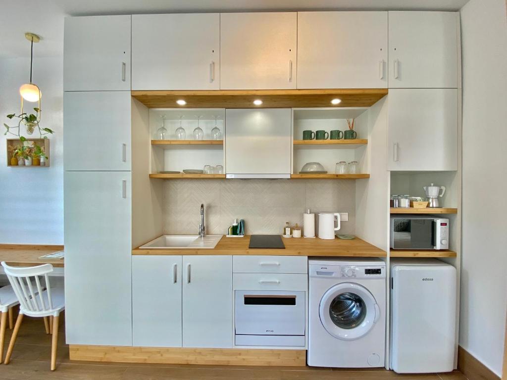 una cucina con mobili bianchi, lavatrice e asciugatrice di LOFT DELUXE ALMA GARDEN a Cordoba