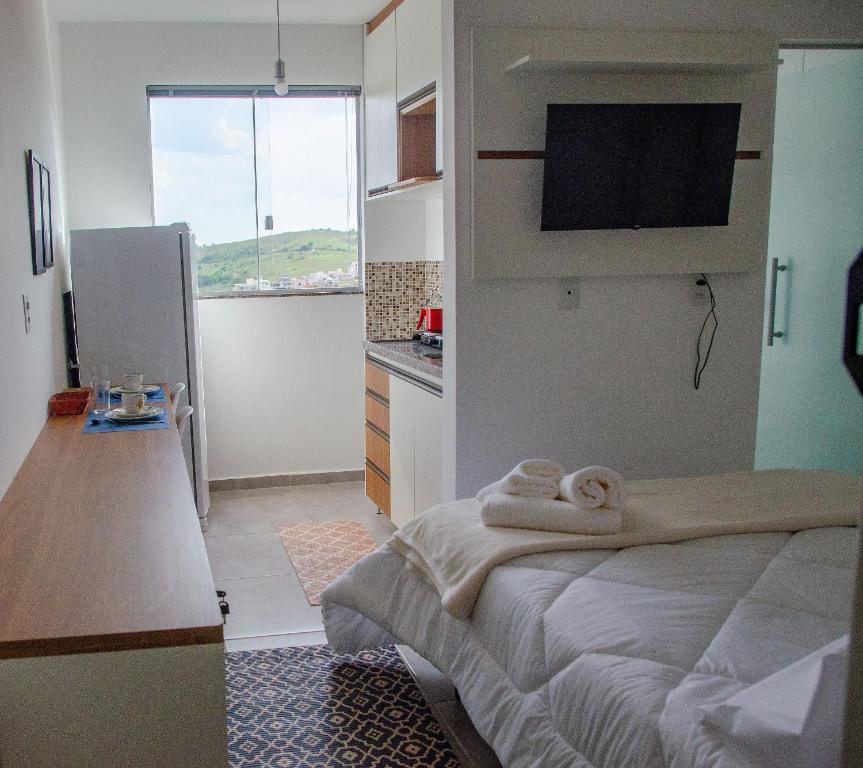 1 dormitorio con 1 cama con toallas en Studio 900m do centro, prédio com piscina, sauna, academia e lavanderia, en São João del Rei