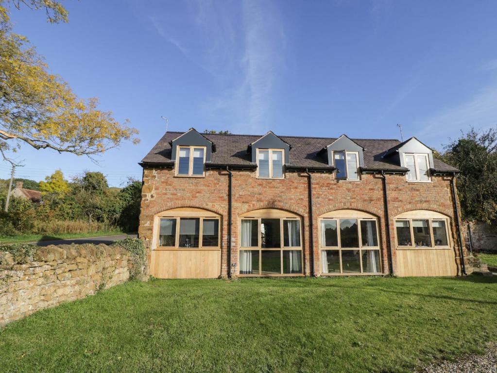 uma grande casa de tijolos com janelas num quintal em Granary Cottage em Southam