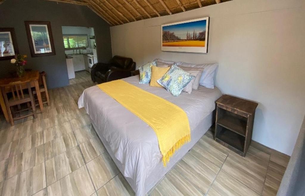 een slaapkamer met een groot bed en een gele deken bij Overflow Cottage in Clarens