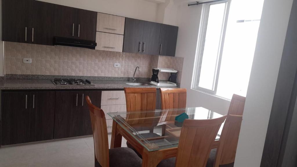 Una cocina con mesa de cristal y armarios de madera. en Hospedaje Santa Rosa de Cabal - Apartamento, en Santa Rosa de Cabal