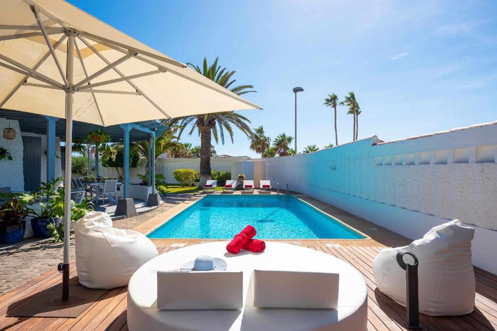 - une piscine avec un parasol, des chaises et une table dans l'établissement Villa Bolsón by W Tenerife, à Puerto de Santiago