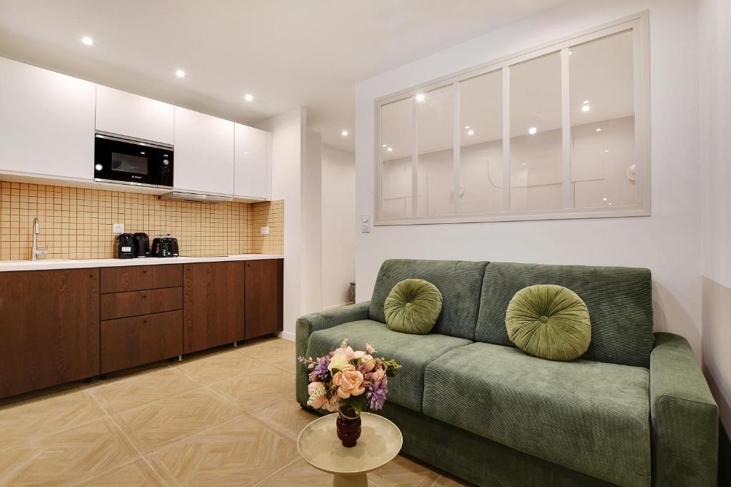 un salon avec un canapé vert et une cuisine dans l'établissement Superbe studio- 5P- Bonne Nouvelle/ Gare de L'est - D, à Paris