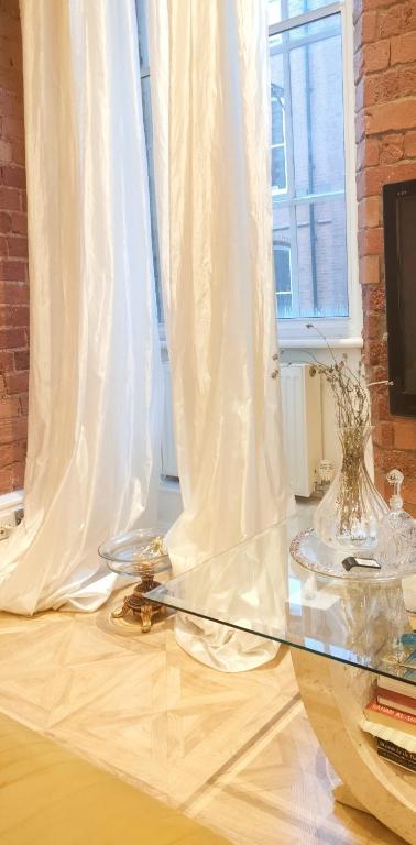 ノッティンガムにあるVersaillesの白いカーテン付きの窓の前のガラステーブル