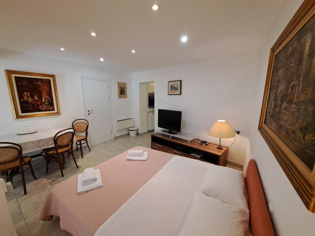 ein Wohnzimmer mit einem Tisch und einem TV in der Unterkunft Apartment Bauk in Draga Bašćanska