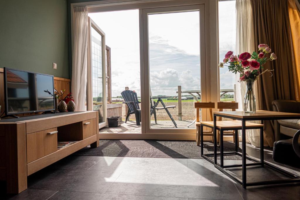 een woonkamer met een televisie en een tafel met bloemen erop bij 4T4 Apartment B in Egmond aan den Hoef