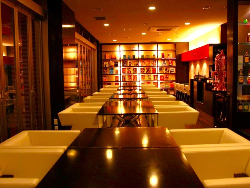un bar con una fila de mesas y sillas blancas en Kurume Hotel Esprit, en Kurume
