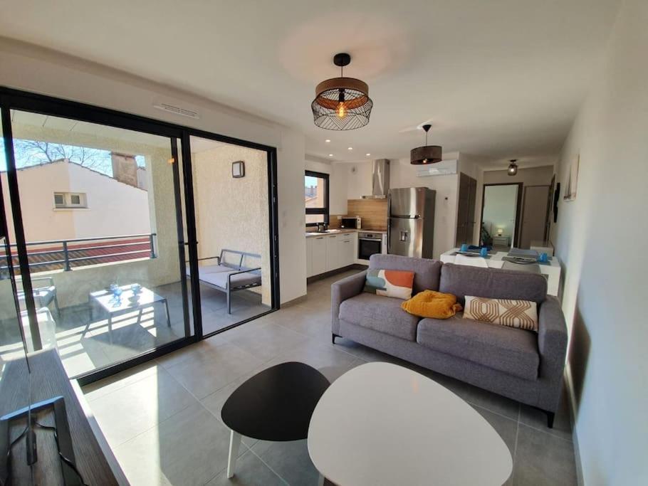 een woonkamer met een bank en een tafel en een keuken bij Appartement neuf très lumineux avec parking in Argelès-sur-Mer