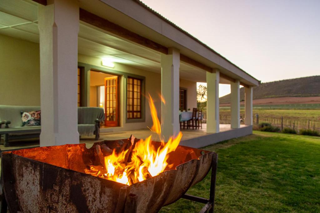 a fire pit in front of a house at Kammanassie Farmstay in Laudina