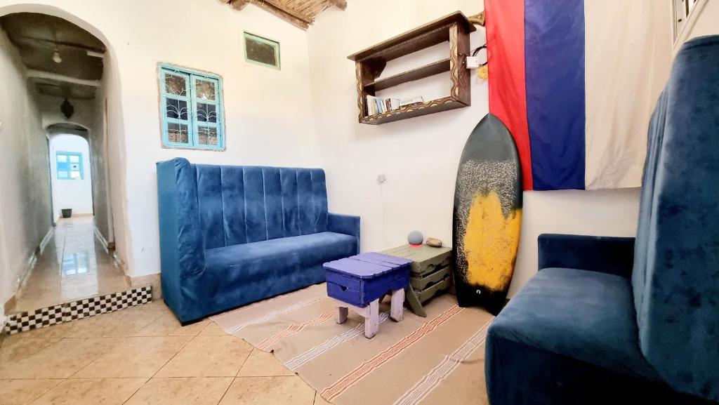 salon z 2 niebieskimi krzesłami i deską surfingową w obiekcie Good Vibes House Imsouane w mieście Imsouane