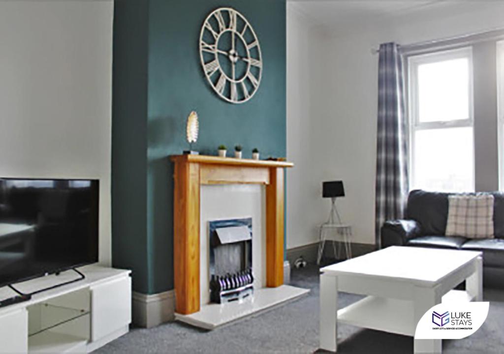 a living room with a fireplace and a clock on the wall at Luke Stays - Brighton Road in Gateshead