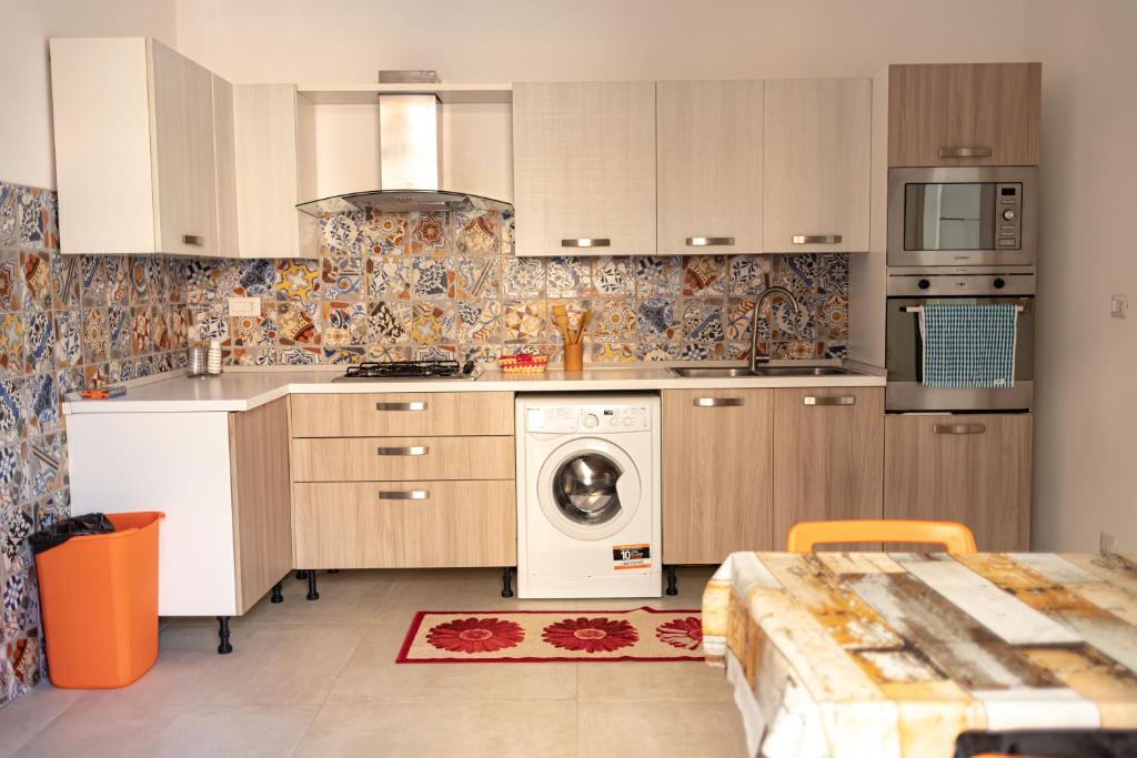 a kitchen with white cabinets and a washing machine at Happy Home - parcheggio gratuito in box in Portici