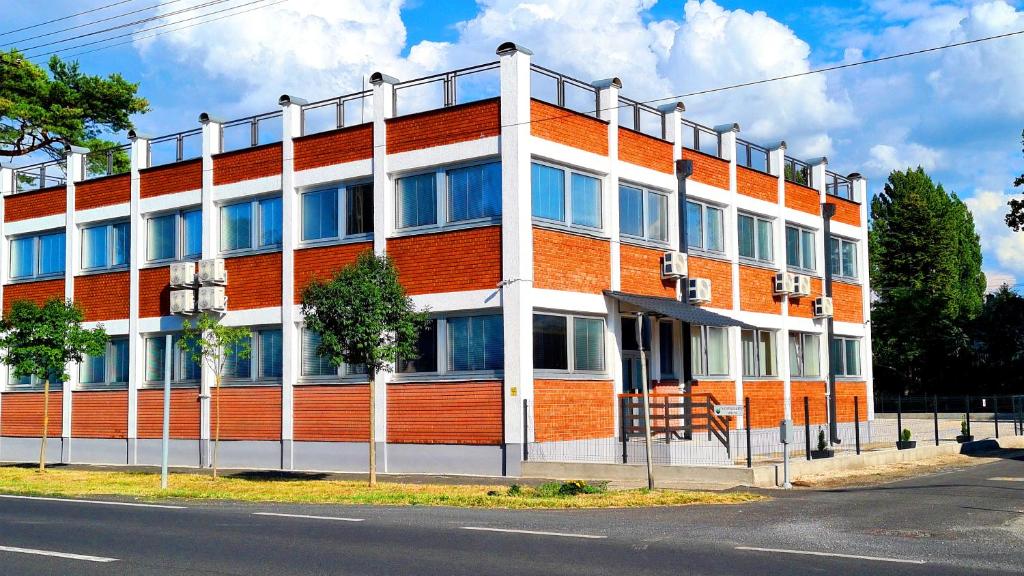 un edificio naranja y blanco al lado de una calle en HÉDER APARTMANOK, en Balatonfenyves