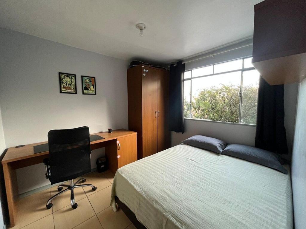 a bedroom with a bed and a desk and a computer at Sobrado Bairro Alto in Curitiba
