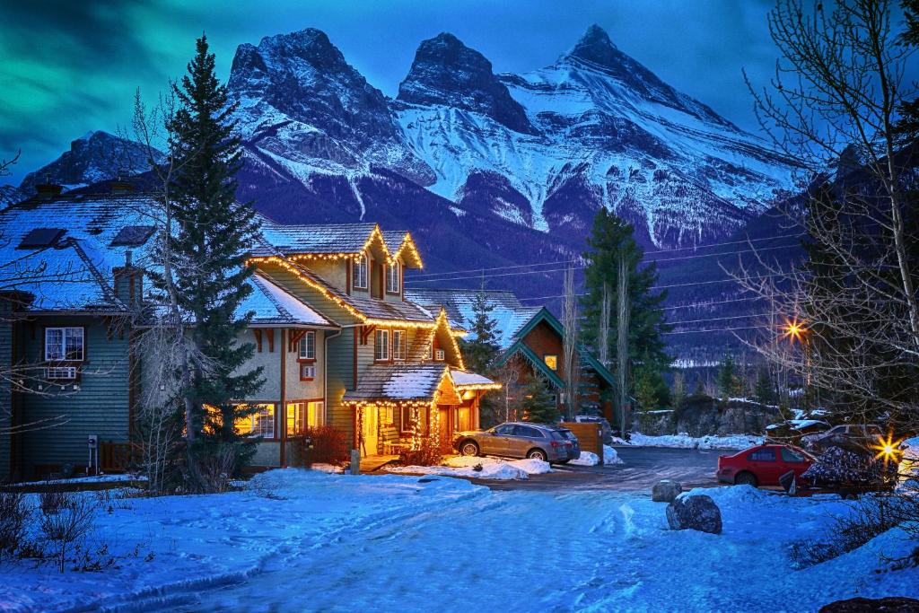 a house with snow covered mountains in the background at Creekside Villa in Canmore