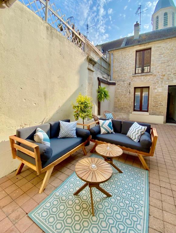 a patio with two couches and two tables at Chambres d'hôtes Le Maroni in Courseulles-sur-Mer