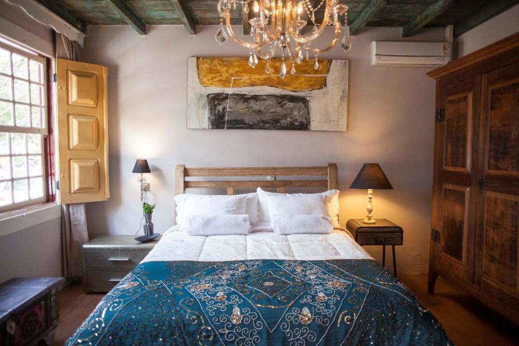 a bedroom with a bed and a chandelier at Pousada Do Largo in Tiradentes
