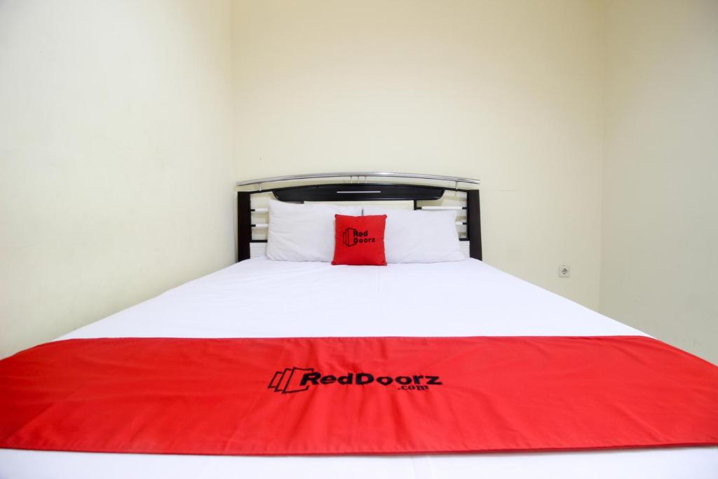 ein Bett mit einer roten Decke darüber in der Unterkunft RedDoorz near Puskesmas Sei Jang Tanjung Pinang in Tanjung Pinang 