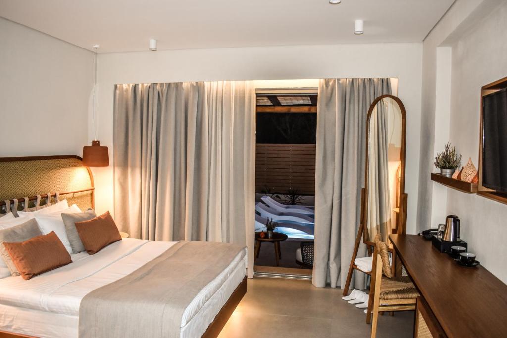 a bedroom with a bed and a desk and a mirror at Mandraki Village Boutique Hotel in Koukounaries
