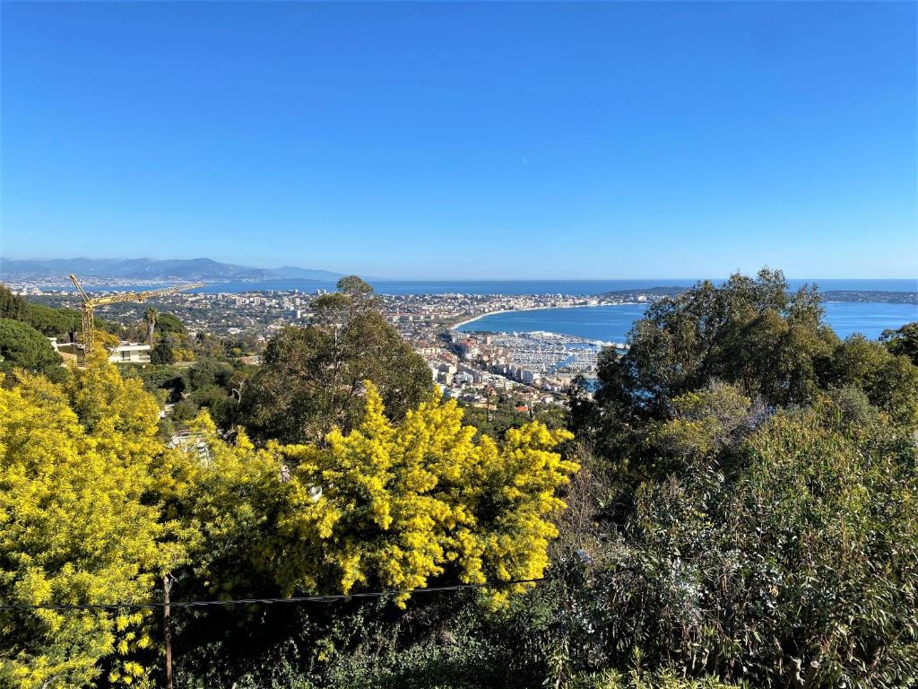a view of a city and the ocean from a hill at VILLA LE MAS D&#39;AZUR BY ESTATESCANNES in Vallauris