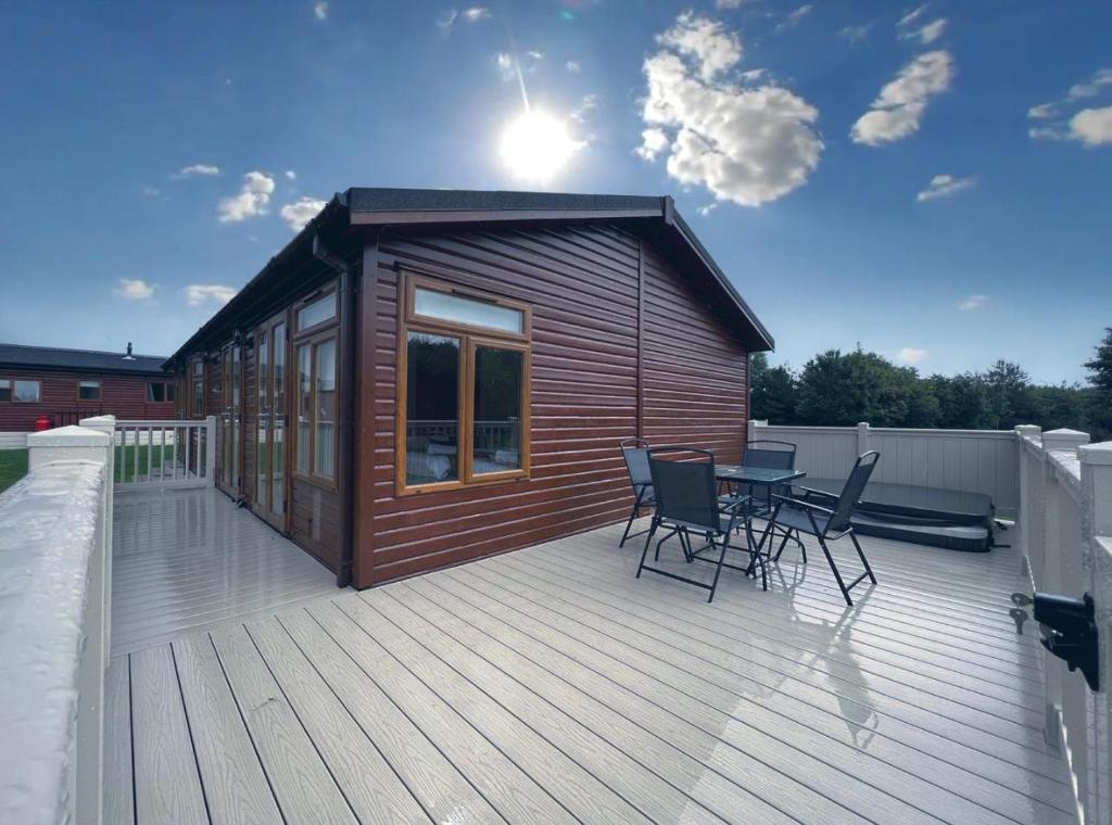 a small cabin with a table and chairs on a deck at Chestnut Lodge With Hot Tub in Malton