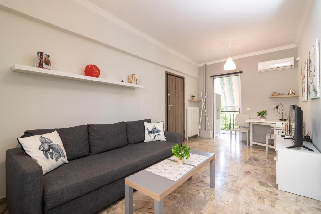 Sala de estar con sofá gris y mesa en Bilocale - Δίχωρο διαμέρισμα δίπλα στα Ψηλαλώνια en Patras