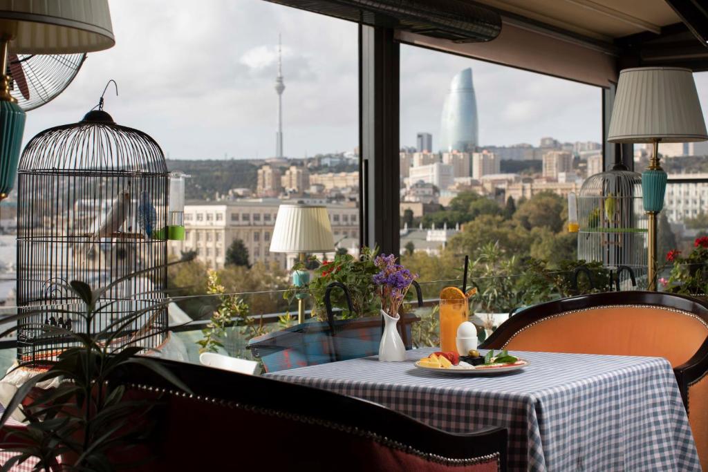 a table with a plate of food and a bird on a balcony at Sapphire City Hotel in Baku