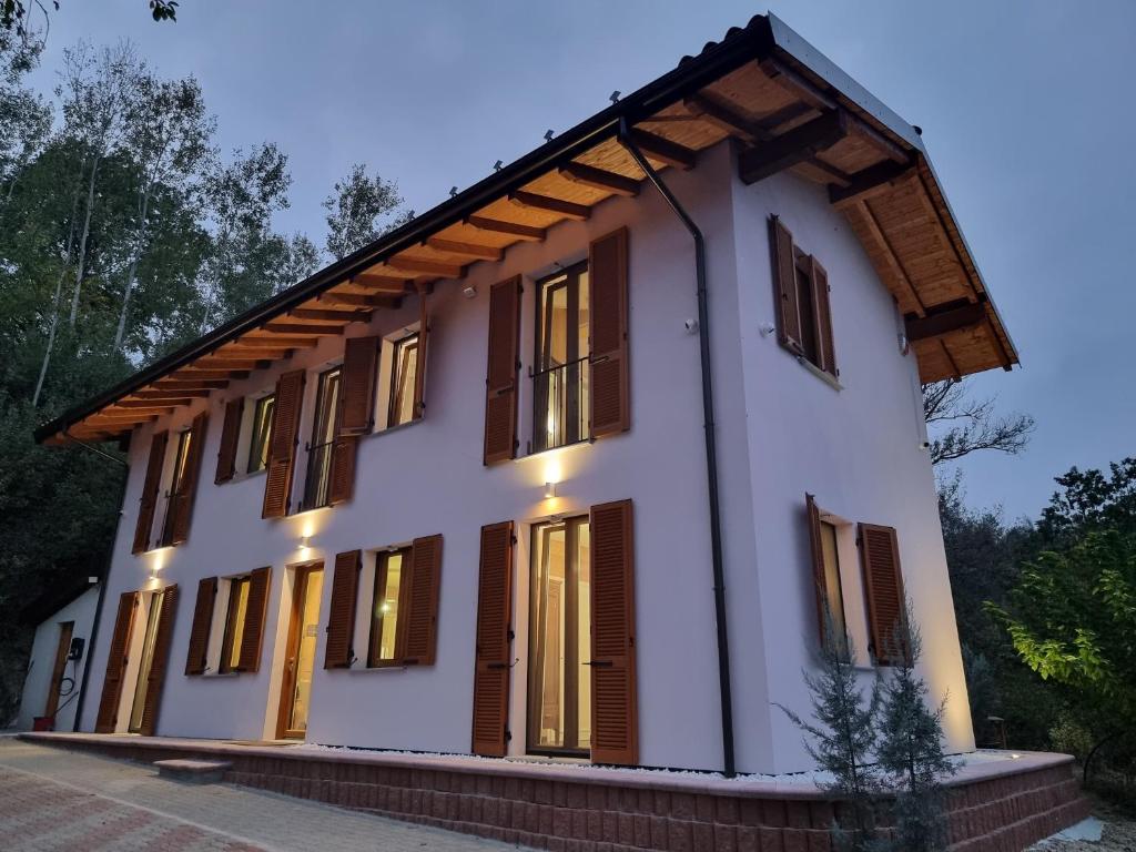 Cette maison est dotée de murs blancs et de fenêtres en bois. dans l'établissement Ca' San Michele, à Asti