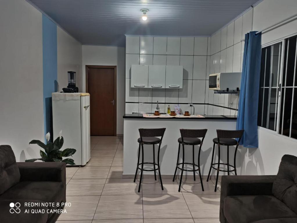 uma cozinha com bancos de bar e uma cozinha com frigorífico em Casa do aconchego ( terreno compartilhado) em Foz do Iguaçu