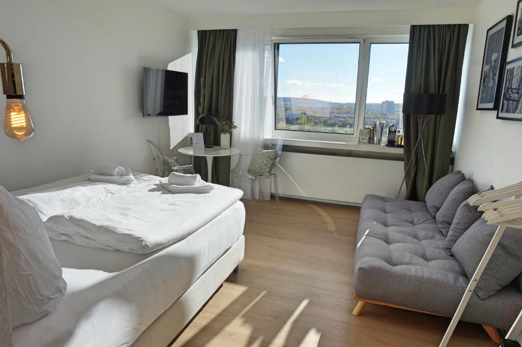 sypialnia z łóżkiem, kanapą i oknem w obiekcie coSI Apartment im SI-Centrum Stuttgart w Stuttgarcie