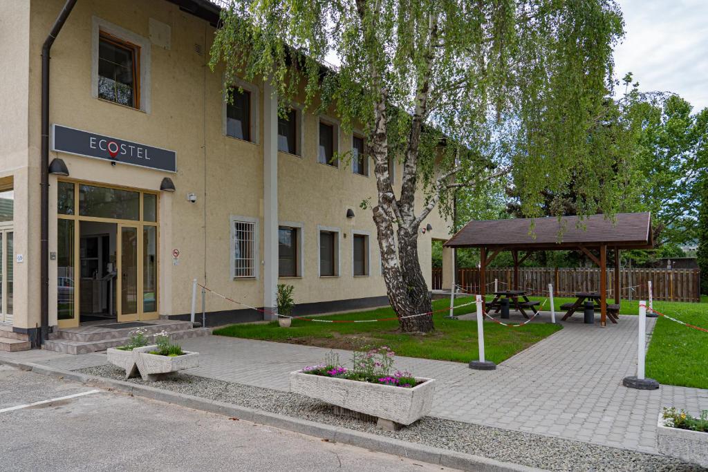 a building with a tree and a picnic table in front of it at Ecostel Budaörs in Budaörs