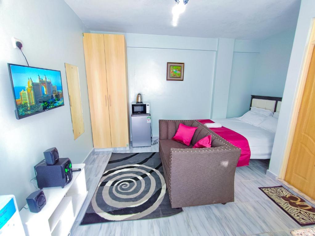 Un dormitorio con una cama, un sofá y una silla. en JSTAY, en Nairobi