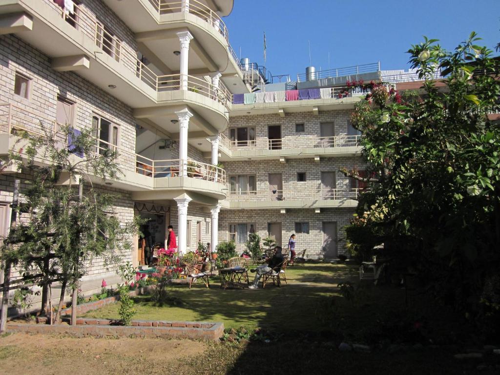 un grande edificio con cortile attrezzato con tavoli e sedie di Hotel Lotus Inn a Pokhara