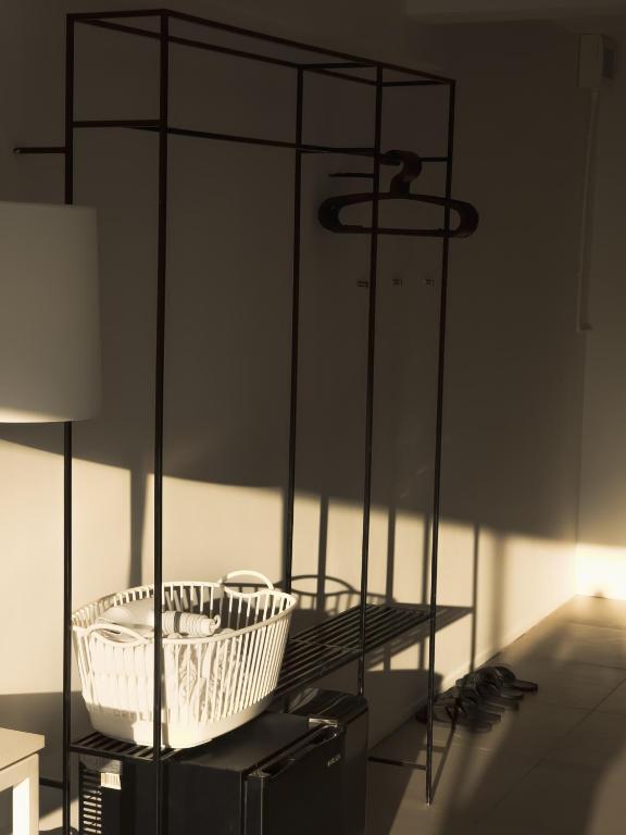 An open black metal clothes rack with a basket and hangers.