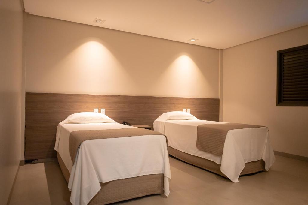 duas camas num quarto com luzes na parede em Bravo's Hotel em Xinguara