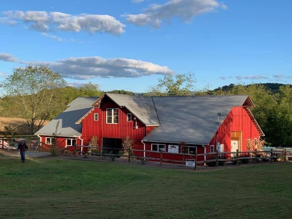 a red barn with a black roof at Tentrr Signature Site - Sunflower Ridge at The Stickley Farm in Bluff City