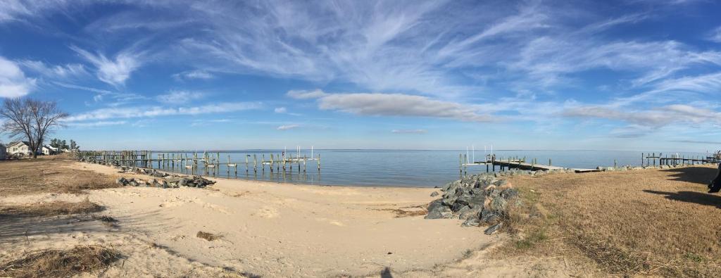 a beach with a pier and the ocean on a cloudy day at Tentrr Signature Site - Potomac Landing in Heathsville