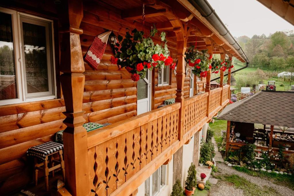 ein Holzhaus mit Blumen auf dem Balkon in der Unterkunft Casa Pintea de Sub Coastă in Breb