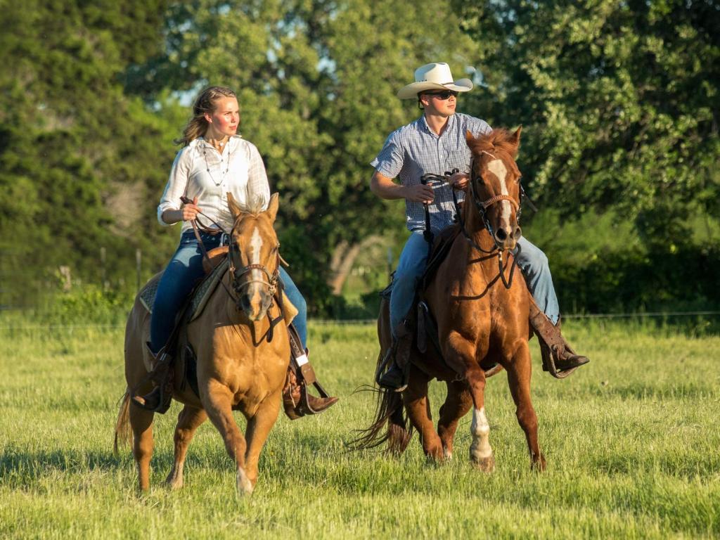 a man and woman riding horses in a field at Tentrr Signature Site - Beautiful Campsite near the Brazos River in Bellmead