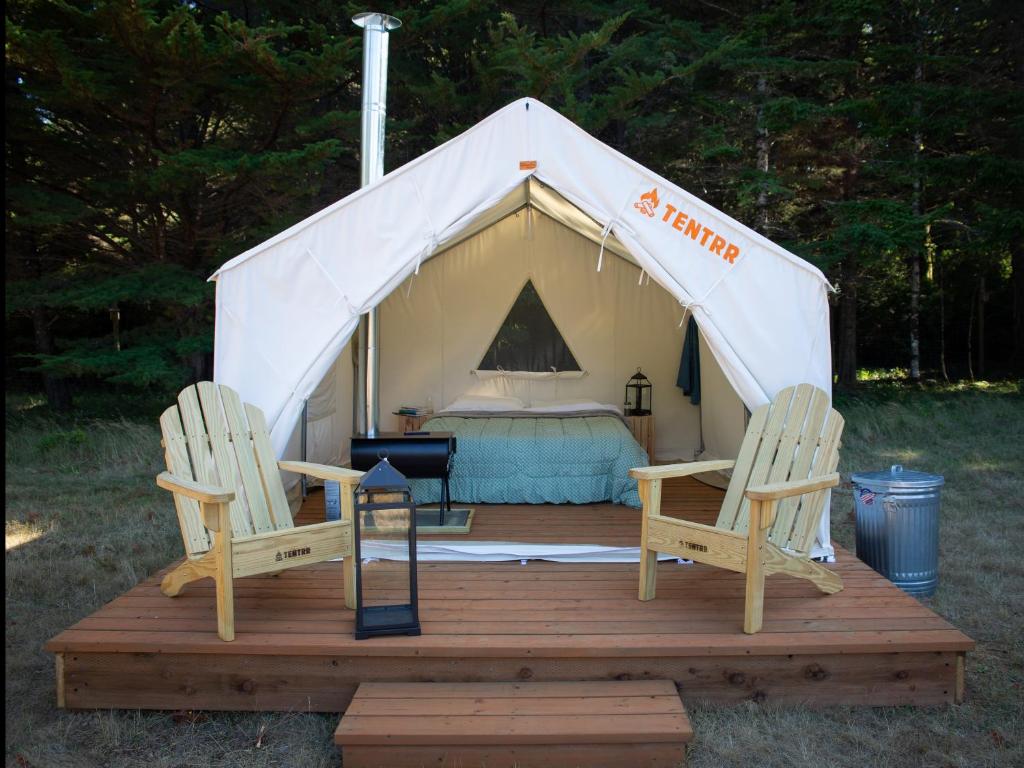 a tent with two chairs and a bed in it at Tentrr - Cranberry Overlook at Black Moon Farms in Langlois