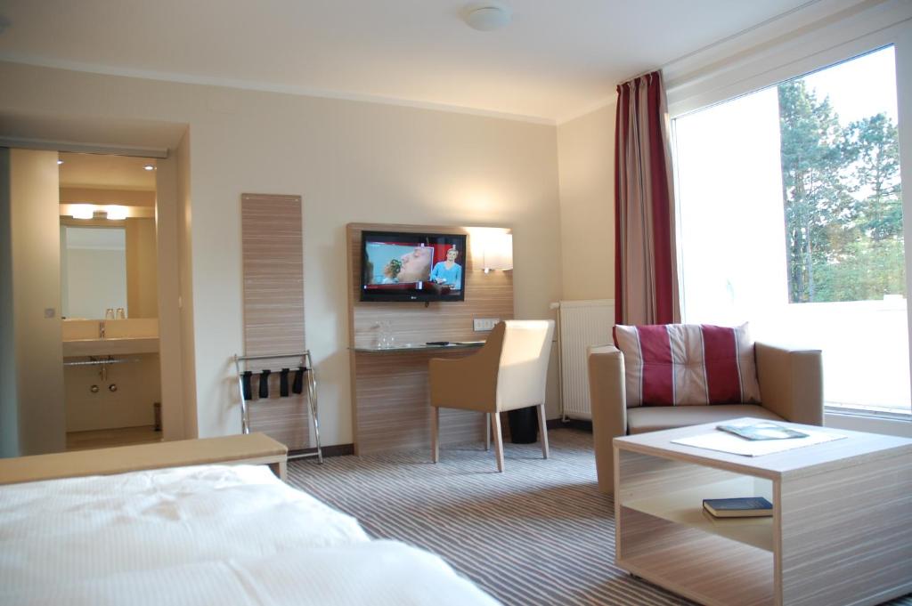 ein Hotelzimmer mit einem Bett, einem Sofa und einem Tisch in der Unterkunft Parkhotel Bad Bevensen in Bad Bevensen
