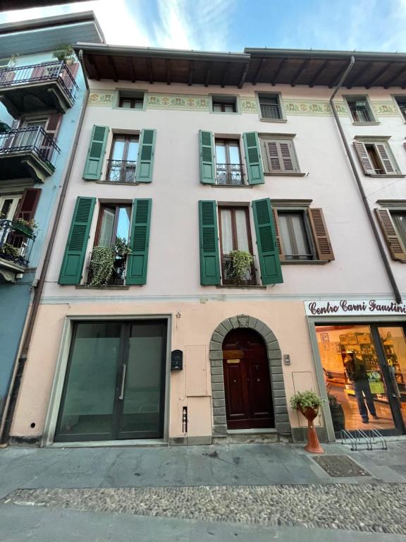 a white building with green shutters on it at Riso e Latte Casa Vacanze in Pisogne