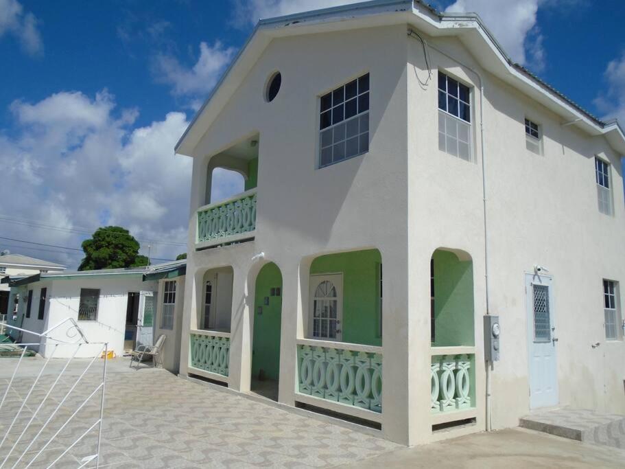 une maison blanche avec des portes et des fenêtres vertes dans l'établissement Simply Beautiful Two Storey home/apt awaits you, à Saint James