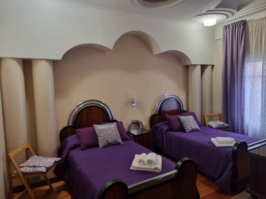 two beds in a room with purple sheets at PisoEncantoLaRioja in Logroño
