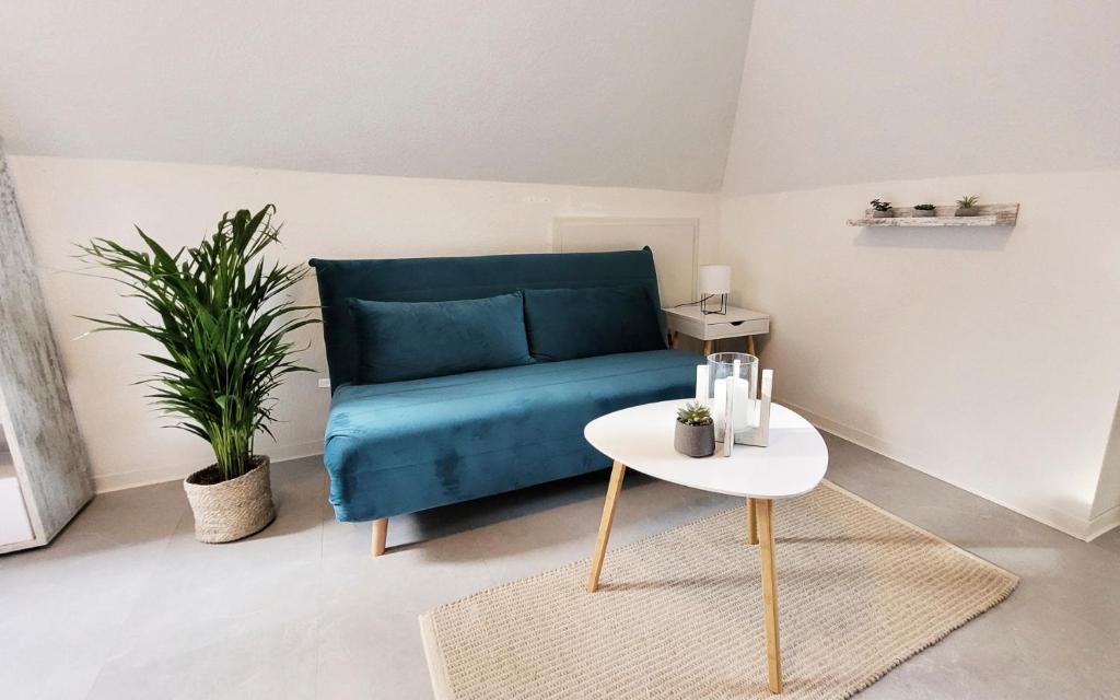- un salon avec un canapé bleu et une table dans l'établissement Wohnung zwischen Nord- und Ostsee mit Fitnessraum, à Ostenfeld