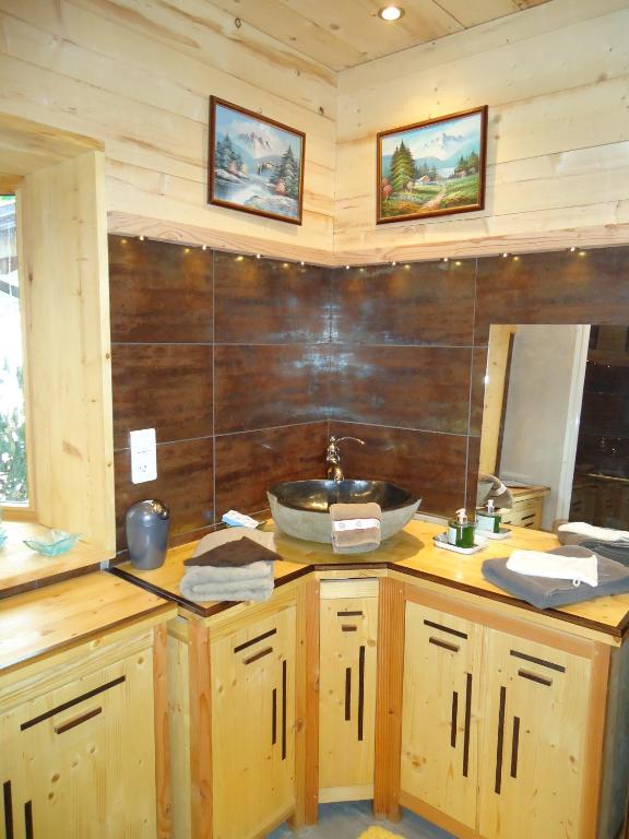 a bathroom with a sink and a wooden wall at L'Eterlou Chambres d'Hote in Albertville