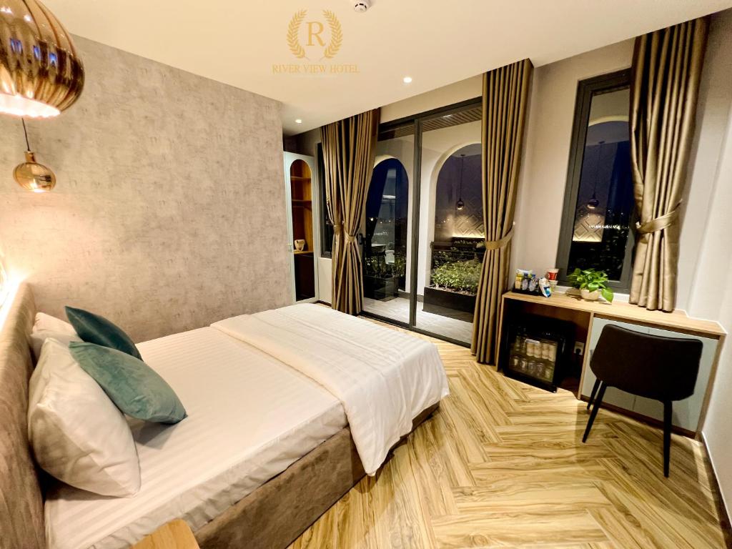 a bedroom with a bed and a desk and windows at River View Hotel in Ho Chi Minh City
